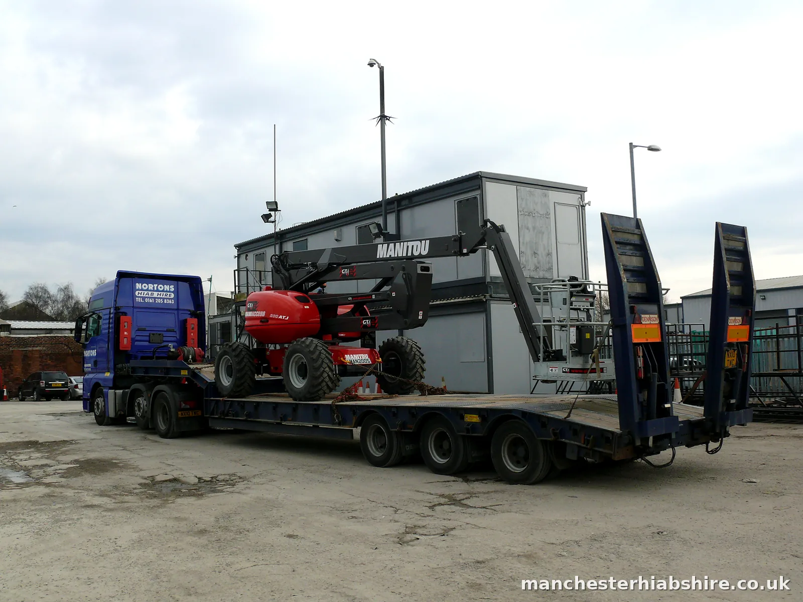 Telescopic boom lift chained down on a low loader trailer