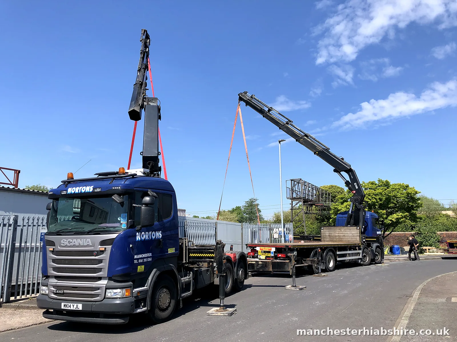 Two HIAB lorries with booms raised and slings rigged for a tandem lift
