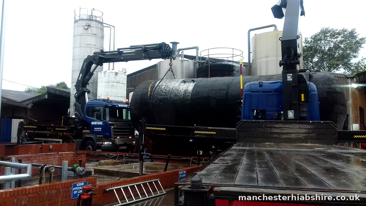 Two HIAB lorries lifting a large tank at a water treatment works