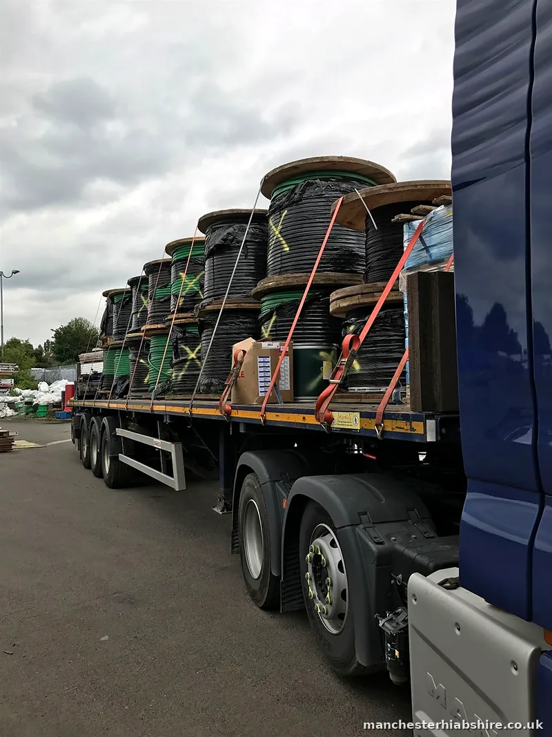 Flat trailer loaded with cable drums and wrapped pallets
