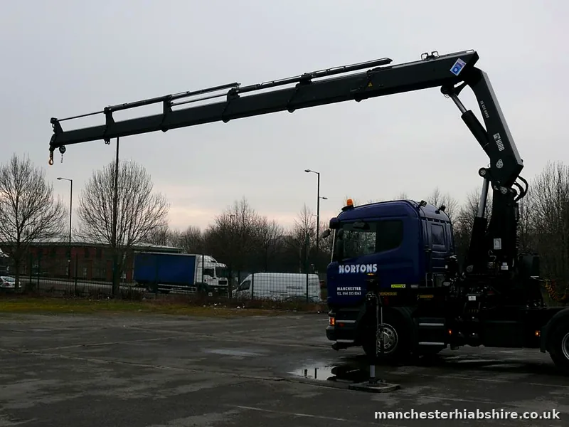 HIAB boom extended horizontally across the yard with outriggers down