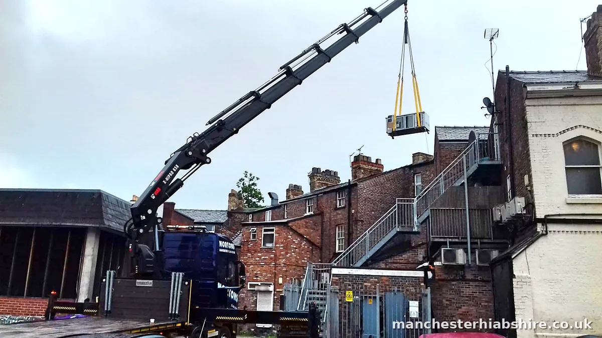 Boom fully extended lifting a unit high over rooftops between terraced houses