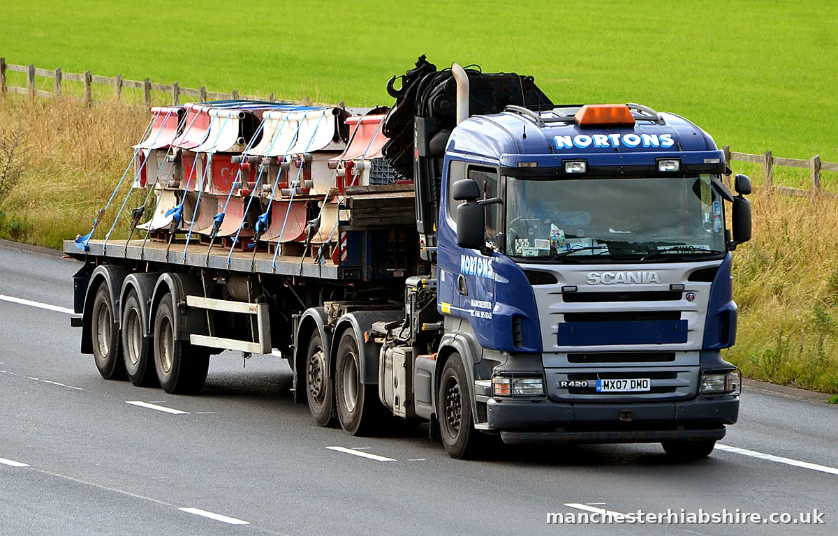 Palletised load strapped across a flat trailer behind a HIAB lorry