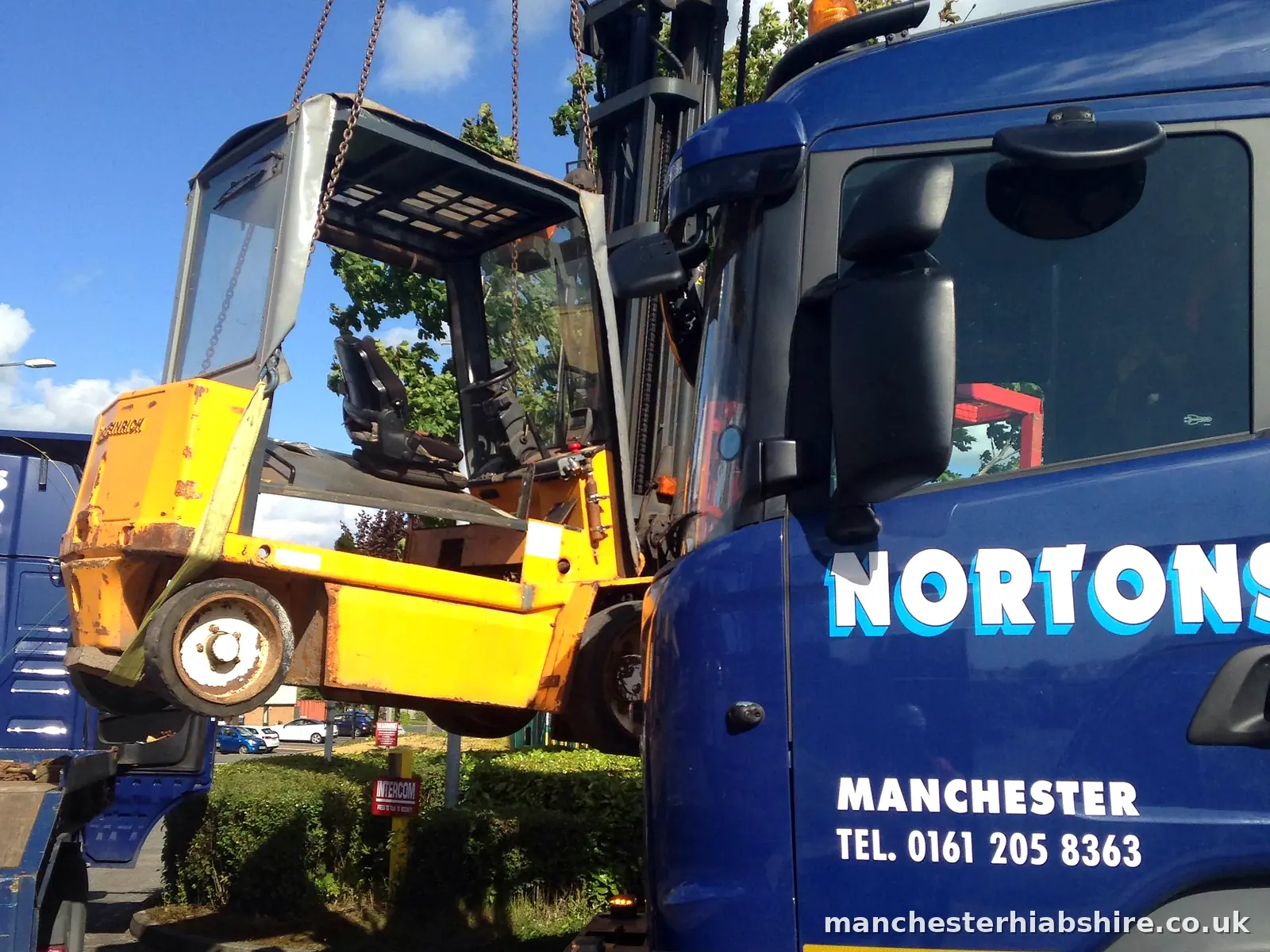 Forklift truck slung on chains beside the HIAB lorry cab during the lift