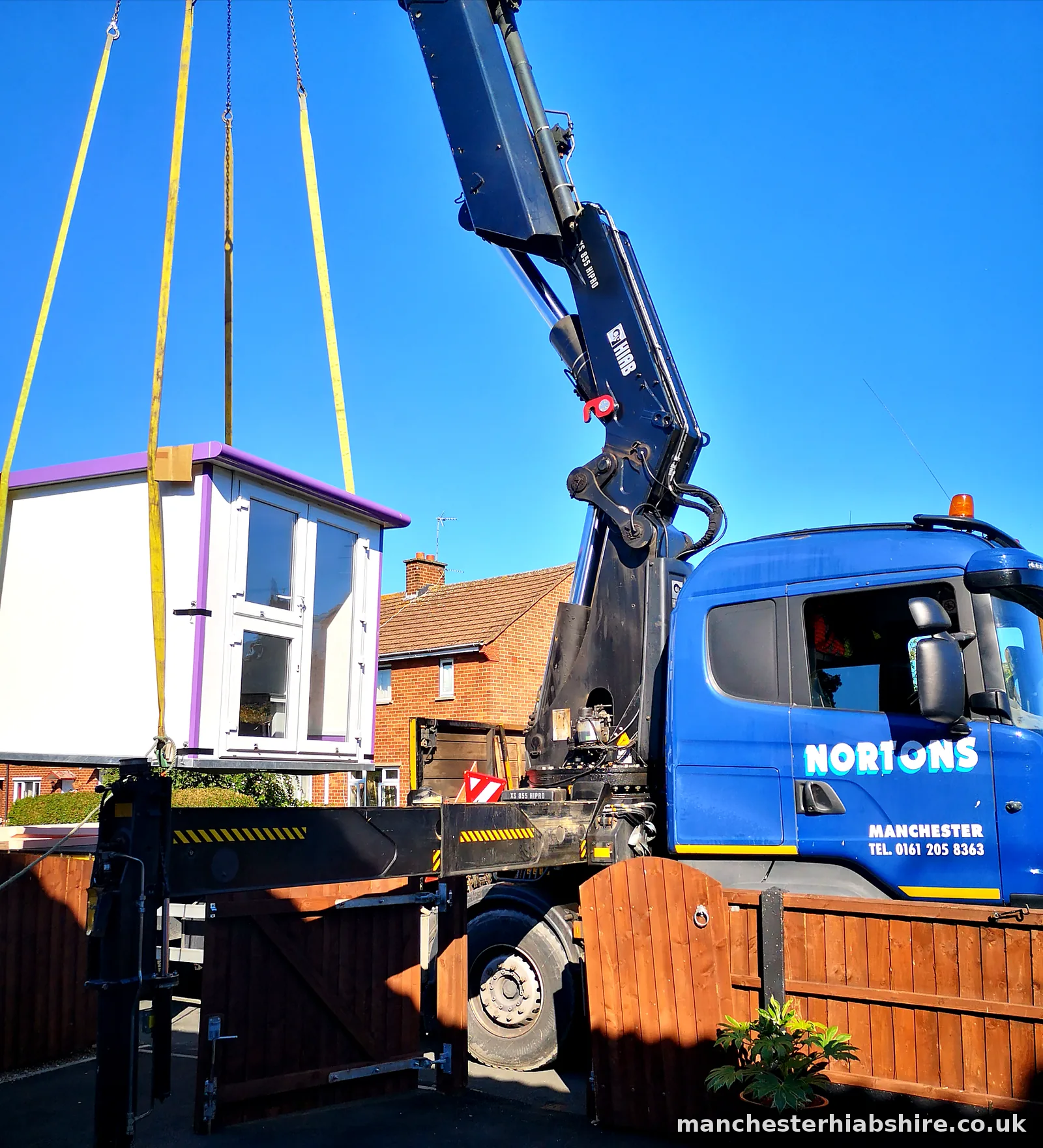 Pod lifted over a garden fence on the lorry mounted crane