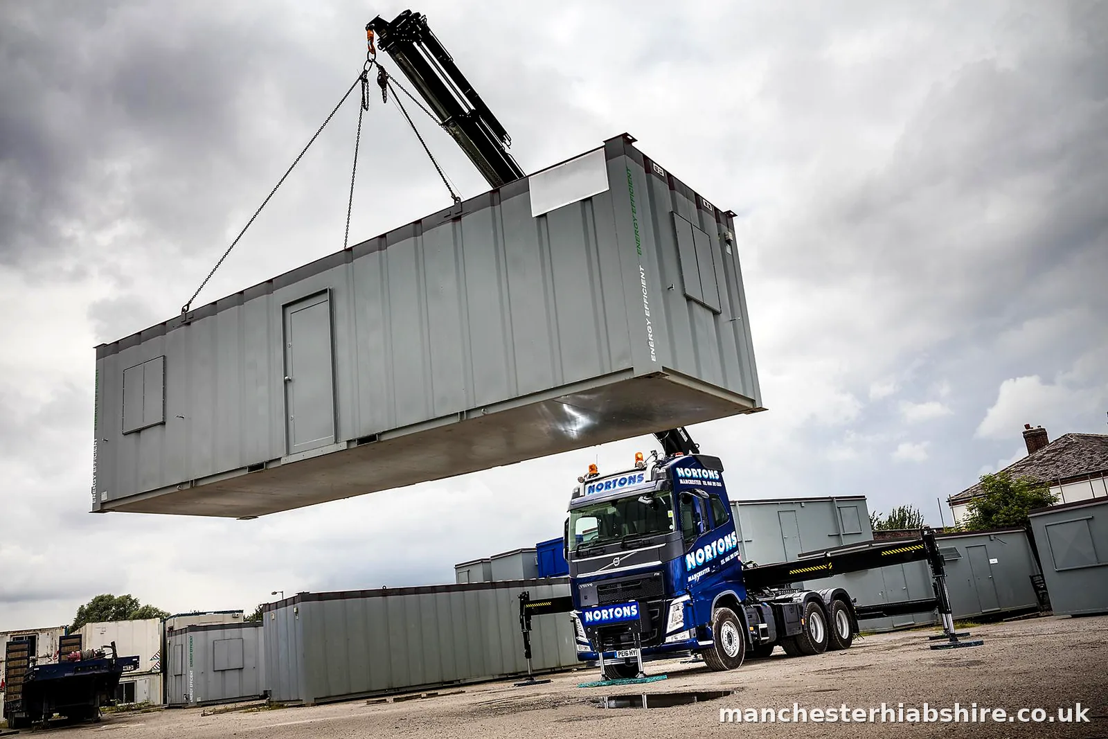 Portable cabin suspended level above the lorry bed on four chains