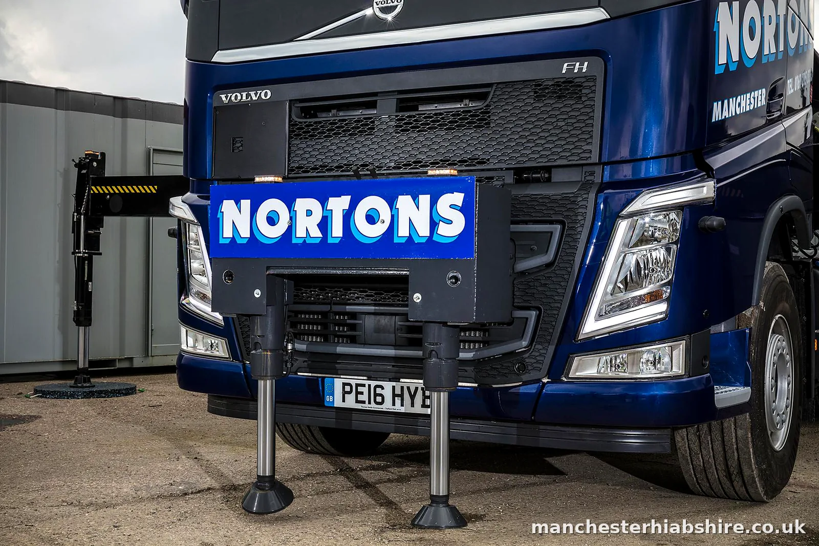 Front of a HIAB lorry with the outrigger legs set down on the yard