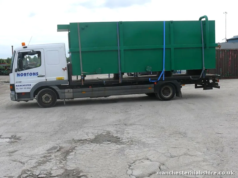 Flatbed lorry carrying a sectional steel water tank, side elevation