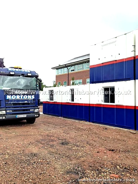 HIAB lorry beside a two storey blue and white cabin complex