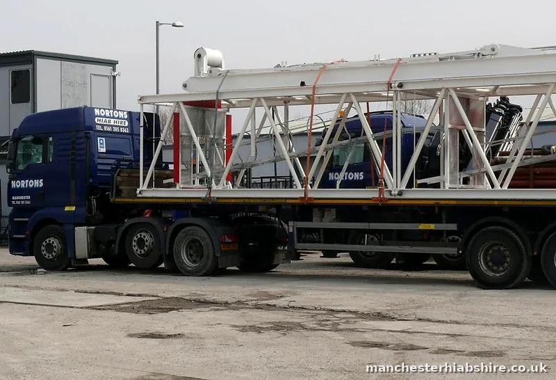 Articulated lorry loaded with white steel jib sections