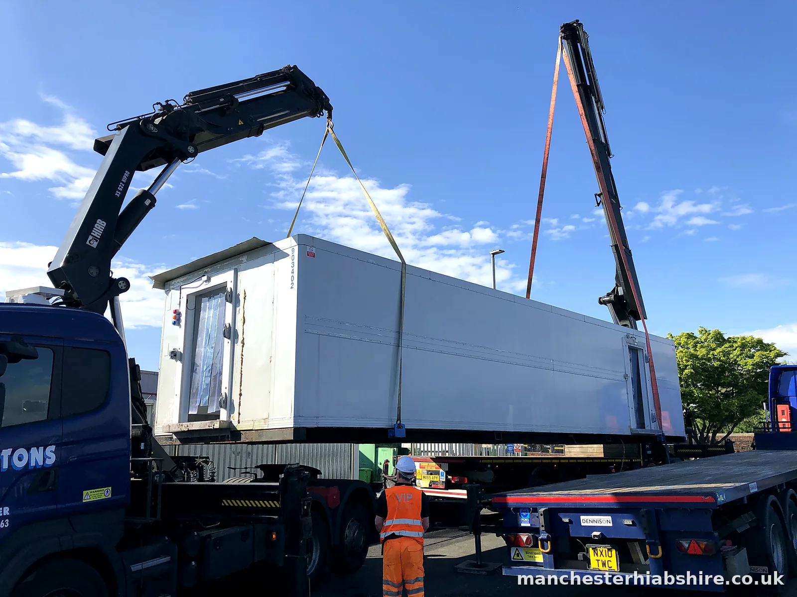 Two HIAB lorries tandem lifting a long insulated unit with a banksman below