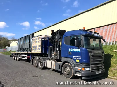 Articulated HIAB loaded with steel lift columns and crates on a flat trailer