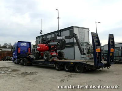 Telescopic boom lift chained down on a low loader trailer