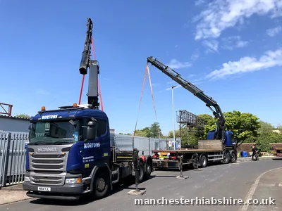 Two HIAB lorries with booms raised and slings rigged for a tandem lift