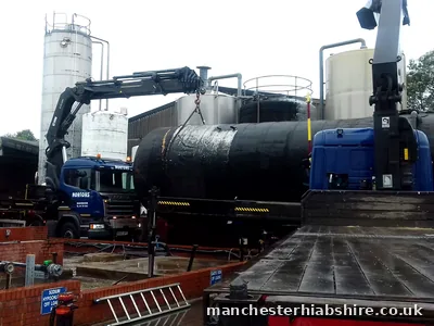 Two HIAB lorries lifting a large tank at a water treatment works