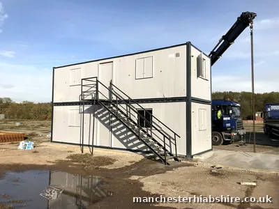 Double stacked cabin block with an external steel staircase and two HIAB lorries