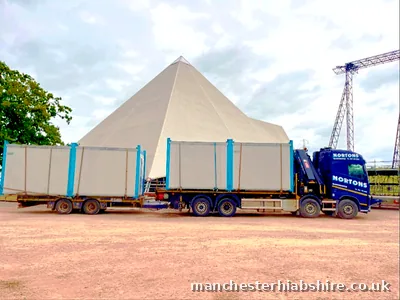 Lorry and trailer loaded with white site cabins at a festival site