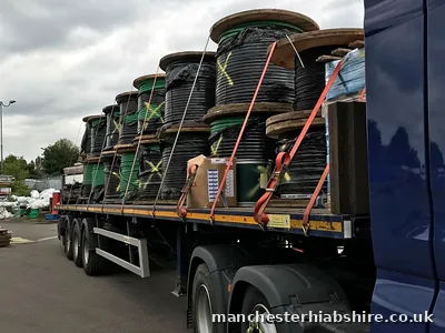 Flat trailer loaded with cable drums and wrapped pallets