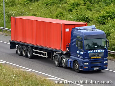 Shipping container carried on the bed of a HIAB lorry at motorway speed