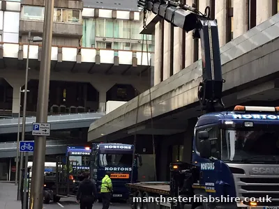 Two HIAB lorries nose to tail under a concrete walkway