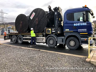 HIAB loaded with two large timber cable drums, crew roping down the load