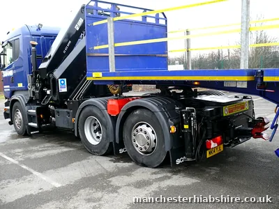 Lorry mounted crane folded down behind the cab of a flatbed lorry