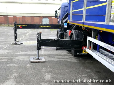 Outrigger legs extended on either side of a lorry before a lift