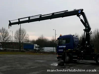 HIAB boom extended horizontally across the yard with outriggers down
