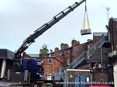 Boom fully extended lifting a unit high over rooftops between terraced houses