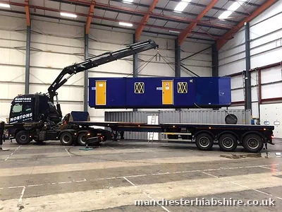 Eight wheel HIAB lifting a unit inside a warehouse above a container on a trailer