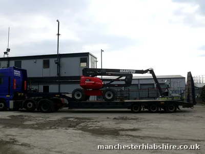 Low loader loaded with a telescopic boom lift, rear three quarter view
