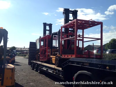 Mast machines chained to a low trailer ready for transport