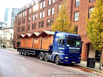 Articulated lorry carrying timber market chalets through the city
