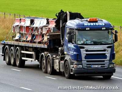 Palletised load strapped across a flat trailer behind a HIAB lorry