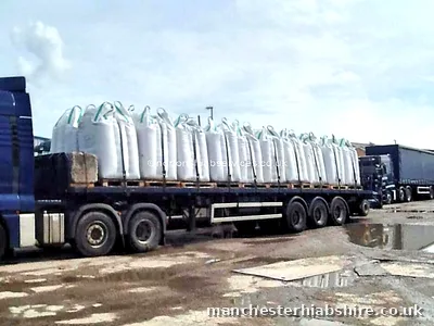 Flat trailer loaded with rows of wrapped and bagged bundles