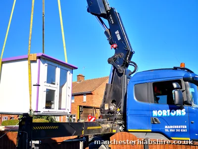 Pod lifted over a garden fence on the lorry mounted crane