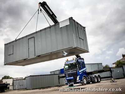 Portable cabin suspended level above the lorry bed on four chains