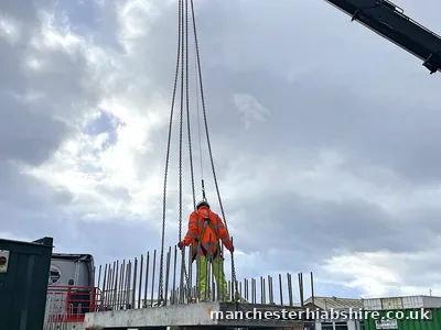 Precast concrete being lifted on site with reinforcement bar in the foreground