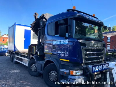 HIAB lorry alongside a blue and white site cabin under a clear sky
