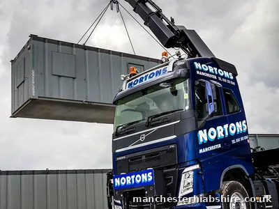Single small cabin lifted on chains by a lorry mounted crane