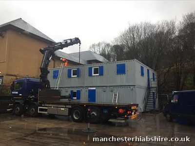 Two storey cabin stack with staircase being installed, crew working on the roof
