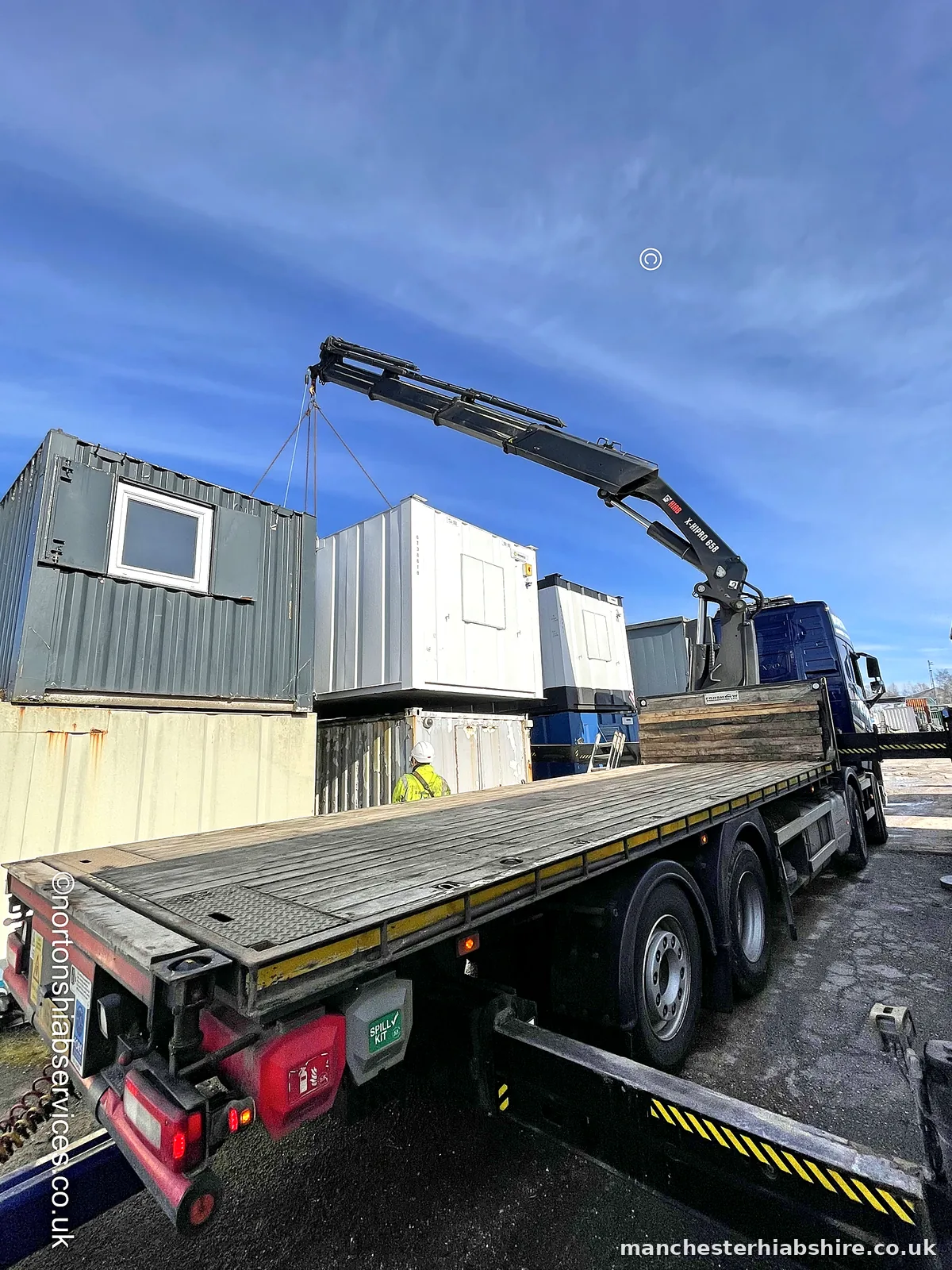 Wagon and drag HIAB lifting a cabin from the trailer